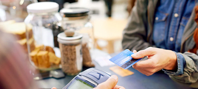 Credit Card picture of customer handing card to merchant to run through the machine.